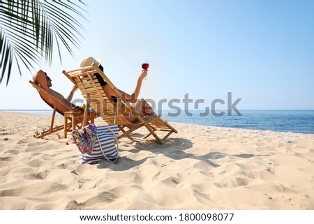 Couple with wine on sunny beach at resort Royalty-Free Stock Photo #1800098077
