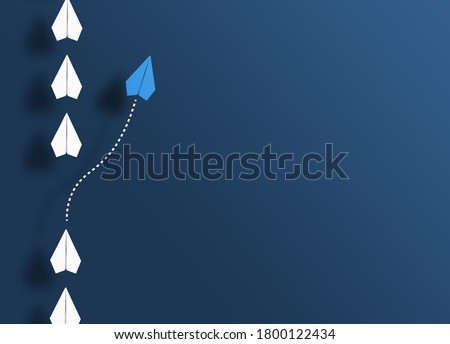 paper planes in a row on blue background and one paper glider going in different direction, breaking new ground and stepping out of the line concept Royalty-Free Stock Photo #1800122434