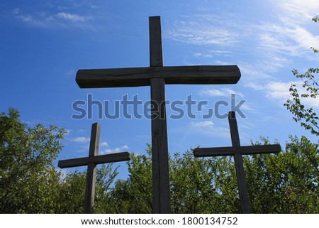 Silhouettes of old wooden crosses in contrasting sunlight. A pilgrimage site on a mountain in the forest. Religious travel to holy places, abstract background