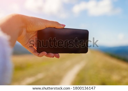 Woman hiker taking selfie with smartphone in mountains on hill peak. Close up of mobile phone screen. Space mockup