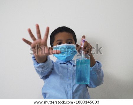 Little boy wearing mask and holding hand gel.
