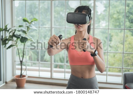 Workout at home. Young woman wearing VR headset doing working out interacting with 3d simulation at home.
