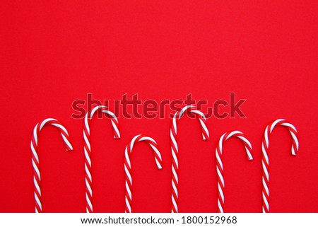 Christmas time. Christmas candy cane on a red background. Christmas time. The view from the top. Flatly. Copyspace.