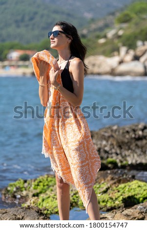woman strolling on the beach with a beach towel
