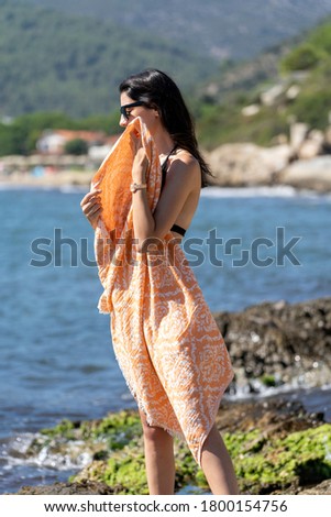 woman strolling on the beach with a beach towel
