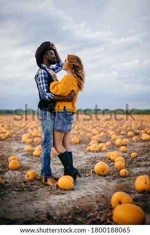 Happy couple stands in pumpkin field and hugs Full-length portrait.