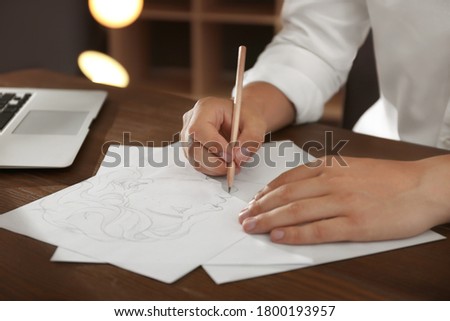 Man drawing portrait with pencil on sheet of paper at wooden table, closeup