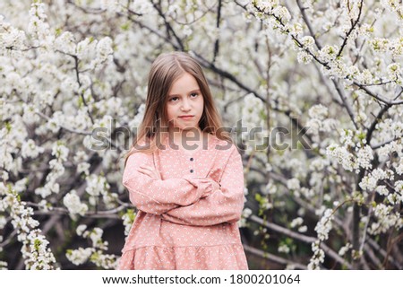 A little child girl stands with her arms folded on her chest and looks with a satisfied expression on her face. Royalty-Free Stock Photo #1800201064