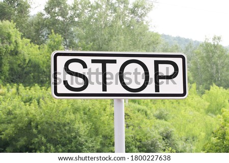 Stop road sign on green trees and forest.