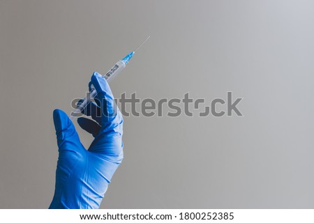 Hand in blue glove holding syringe with copy space. Syringe with sharp needle in hand. Medical treatment concept. Laboratory backgrouund. Medicare concept. Vaccination concept.  Royalty-Free Stock Photo #1800252385
