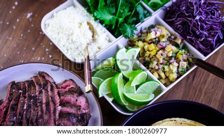 Marinated flank steak taco bar with multiple garnishes and salsa