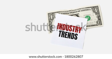 1 dollar bill and white notepad sheet on the white background. INDUSTRY TRENDS text.