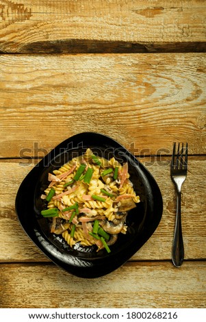 plate with pasta with ham and mushrooms in a creamy sauce on the table.
