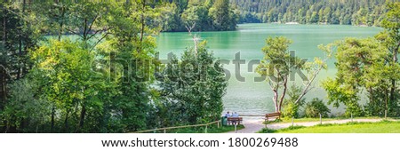 Beautiful German lake Thumsee in Alpine mountains among the green forest. Popular walking trail in summer sunny day. Berchtesgaden National Park, Germany.