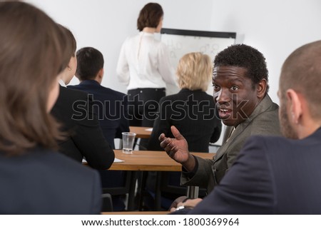 African American business male talking with people during conference in office room