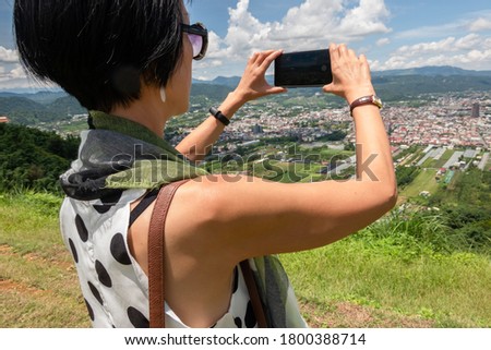 Asian woman stand in a hill take picture under blue sky