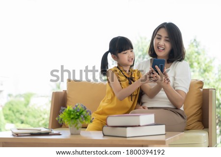 Asian mother and daughter kid using smartphone at home, Homeschool learning concept Royalty-Free Stock Photo #1800394192