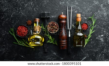 Spices, herbs and oil on a black stone table. Top view. Free space for your text.
