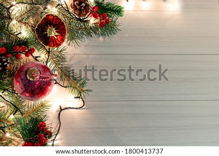 Christmas decoration with spruce branches with a red ball and a garland. Winter holiday light decoration. Top view.