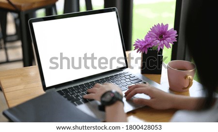 Cropped image of the hand is using an empty screen computer laptop at the wooden working desk.
