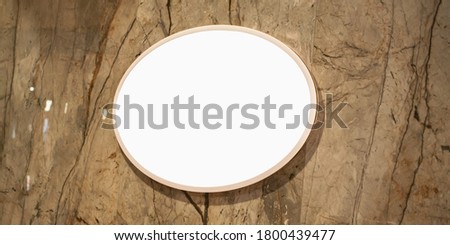 white blank circle display with mockup hanging on marble wall of fashion store closeup