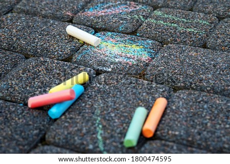 Colored chalk on playground with drawings on street.children drawing on the street. drawing lessons and creativity for kids in kindergarten, child development center. street art on asphalt, pavement.