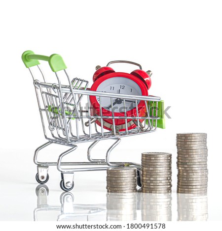 Close-up of red watch in shopping cart and a pile of coins on a white background. Business Finance and Money concept. Save money to prepare for the future.