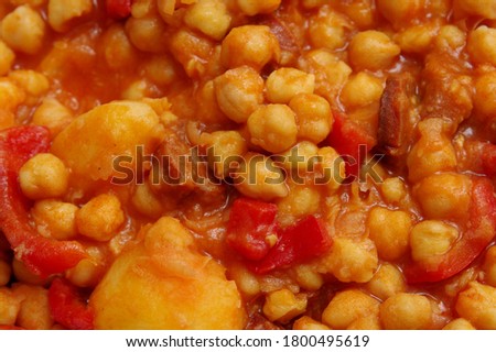 Close view of Chickpeas plate with ham, sausage, red pepper, potatoes with red and thick broth