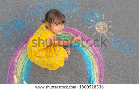 A child draws a rainbow on the asphalt. Selective focus. kid. Royalty-Free Stock Photo #1800518536