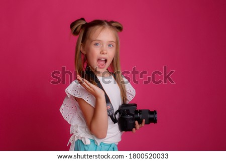 Portrait of a girl traveler, about traveling, holding a camera in her hands, on a pink background