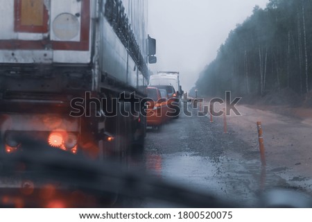 Red light from the headlights ahead of Manina standing in the rain.  Rainy road with poor visibility. Traffic jam, congestion of cars on the highway. Slow-motion driving in the rain.