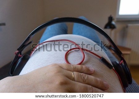 Headphones on a baby belly. Pregnant woman is playing music to her unborn baby.