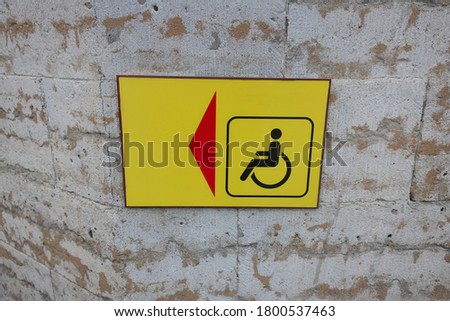 red arrow on yellow background indicating disabled parking space                     