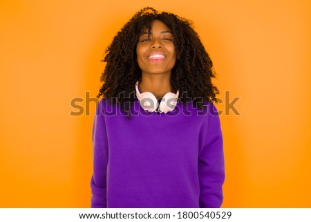 Beautiful Young  caucasian woman with happy and funny face smiling and showing tongue. Wearing casual clothes and standing against gray studio background.