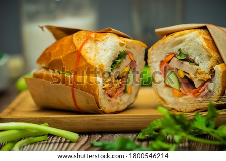 Snack at break time. Famous Vietnamese food is Banh mi thit and black coffee, popular street food from bread stuffed with raw material: pork, ham, pate, egg and fresh herbs.Typical Vietnamese sandwich Royalty-Free Stock Photo #1800546214