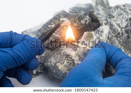 Asbestos fibers over a burning match. Non-flammable properties of chrysotile asbestos, fire-fighting material. Royalty-Free Stock Photo #1800547423