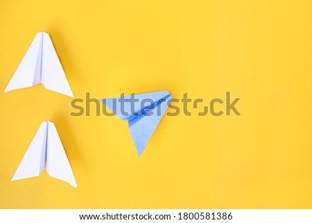Paper airplanes of white and blue colors on a yellow background. Concept.
