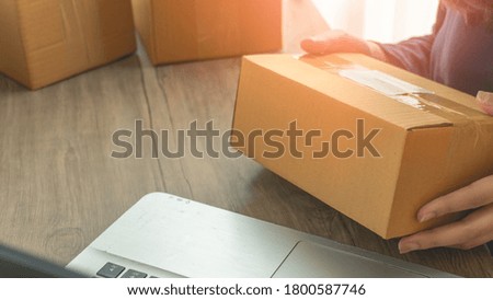 Woman hands holding a parcel and laptop in the foreground with copy space. Business at home concept. Business start up SME concept.