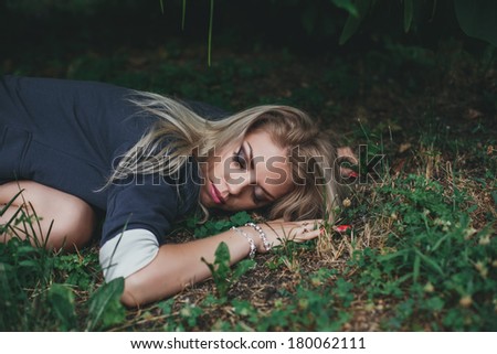 Blonde woman model sleeping on grass in the green park  