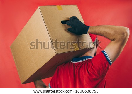 Guy with a cardboard box in his hands. Delivery service concept on red background