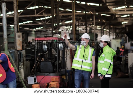 Caucasian maintenance engineers wearing masks Walking to explore old machinery condition To define maintenance plans in industrial plants During the production shutdown during the coronavirus outbreak Royalty-Free Stock Photo #1800680740
