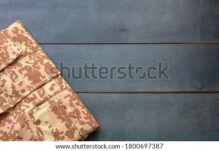 US army acu digital desert uniform shirt on blue wooden background. Military camouflage digital desert pattern folded shirt detail, copy space, template