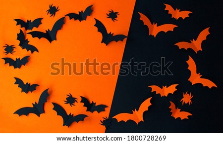 Halloween concept - black and orange paper bats flying over black and orange background