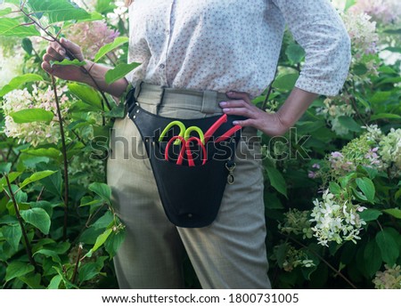Girl florist with floral holster in the garden Royalty-Free Stock Photo #1800731005
