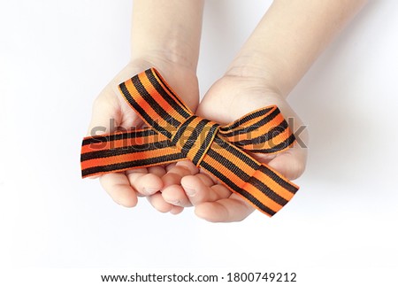 orange and black striped ribbon symbol on May 9 in hands isolated on white background
