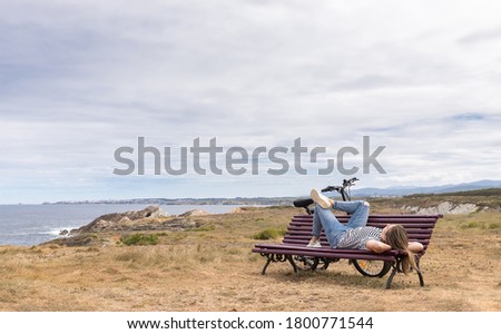 Woman lying on a wooden bench relaxing in front of the sea