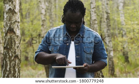 An african man using the tablet in the forest. wireless or future technology concept. High quality photo