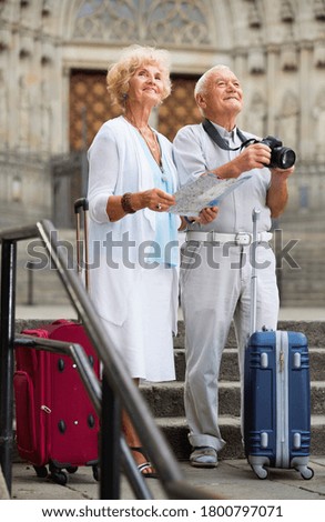 Happy positive smiling mature couple making photo and using map during joint vacation