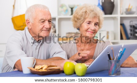 Portrait of cheerful mature spouses using laptop at home