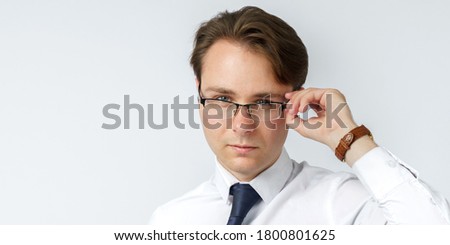 Portrait of a businessman adjusting his glasses. White background. Business and finance concept